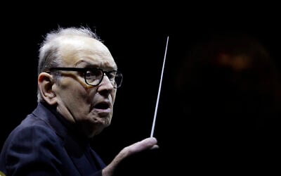 In this March 6, 2018, photo, Italian composer Ennio Morricone directs an ensemble during a concert of his "60 Year Of Music World Tour" in Milan, Italy. (AP Photo/Luca Bruno)