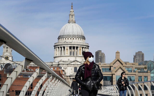 People wear masks as they walk in London over the River Thames on Millennium Bridge near St Paul's Cathedral, seen in the background, March 22, 2020. (AP Photo/Kirsty Wigglesworth) People wear masks as they walk in London over the River Thames on Millennium Bridge near St Paul's Cathedral, seen in the background, March 22, 2020. (AP Photo/Kirsty Wigglesworth)