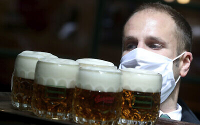 Illustrative: A waiter wears a face mask as he carries beer through a restaurant in Vienna, Austria, May 14, 2020. (AP Photo/Ronald Zak)
