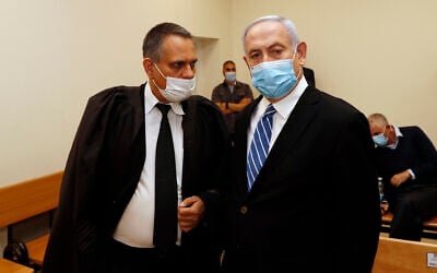 Prime Minister Benjamin Netanyahu (R) talks with attorney Micha Fettman (L) inside the court room as his corruption trial opens at the Jerusalem District Court, May 24, 2020 (Ronen Zvulun/ Pool Photo via AP)