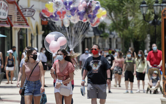 Guests required to wear masks because of the coronavirus pandemic stroll through the Disney Springs shopping, dining and entertainment complex, on June 16, 2020, in Lake Buena Vista, Florida. (AP Photo/John Raoux) Guests required to wear masks because of the coronavirus pandemic stroll through the Disney Springs shopping, dining and entertainment complex, on June 16, 2020, in Lake Buena Vista, Florida. (AP Photo/John Raoux)