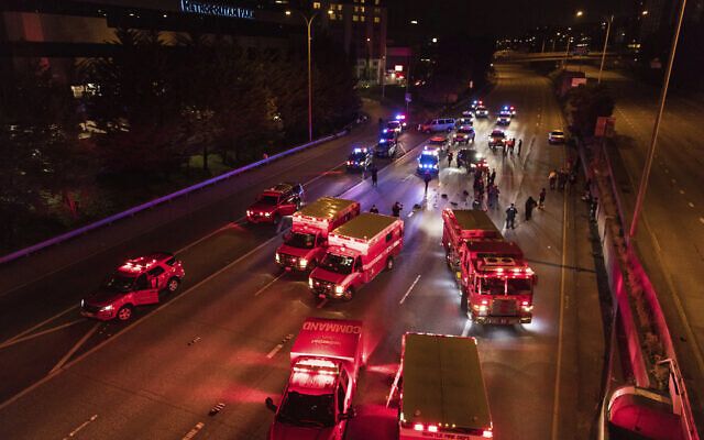 Emergency personnel work at the site where a driver sped through a protest-related closure on the Interstate 5 freeway in Seattle, authorities said, July 4, 2020 (James Anderson via AP) Emergency personnel work at the site where a driver sped through a protest-related closure on the Interstate 5 freeway in Seattle, authorities said, July 4, 2020 (James Anderson via AP)