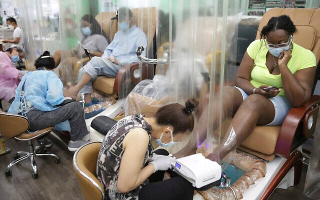 Customers sit behind plastic curtains while getting a pedicure at HT&V Nails in New York, July 6, 2020 (AP Photo/Seth Wenig) Customers sit behind plastic curtains while getting a pedicure at HT&V Nails in New York, July 6, 2020 (AP Photo/Seth Wenig)