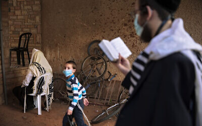 Jews pray next to their house as synagogues are limited to 20 people as per the government's measures to help stop the spread of the coronavirus in Bnei Brak, Israel, July 9, 2020. (Oded Balilty/AP) Jews pray next to their house as synagogues are limited to 20 people as per the government's measures to help stop the spread of the coronavirus in Bnei Brak, Israel, July 9, 2020. (Oded Balilty/AP)