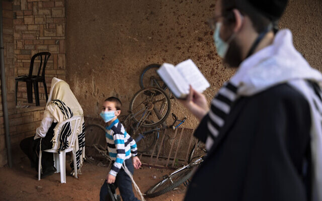 Jews pray next to their house as synagogues are limited to 20 people as per the government's measures to help stop the spread of the coronavirus in Bnei Brak, Israel, July 9, 2020. (Oded Balilty/AP) Jews pray next to their house as synagogues are limited to 20 people as per the government's measures to help stop the spread of the coronavirus in Bnei Brak, Israel, July 9, 2020. (Oded Balilty/AP)