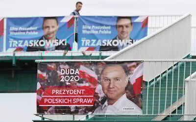 A man walks by campaign posters showing two contenders in Poland's presidential election runoff, conservative incumbent President Andrzej Duda and his rival, liberal Warsaw Mayor Rafal Trzaskowski, top, in Warsaw, Poland, July 11, 2020. (AP Photo/Czarek Sokolowski)