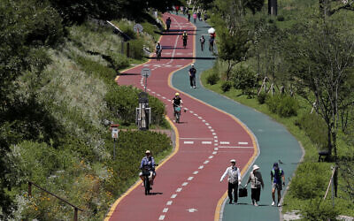 Visitors wearing face masks to help protect against the spread of the new coronavirus take a walk at a park in Seoul, South Korea, July 15, 2020. (AP Photo/Lee Jin-man)
