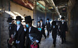 A group of ultra-Orthodox Jewish youth wear protective face masks following government measures to help stop the spread of the coronavirus, as they walk in Jerusalem's Old City, July 16, 2020. (AP/Oded Balilty)