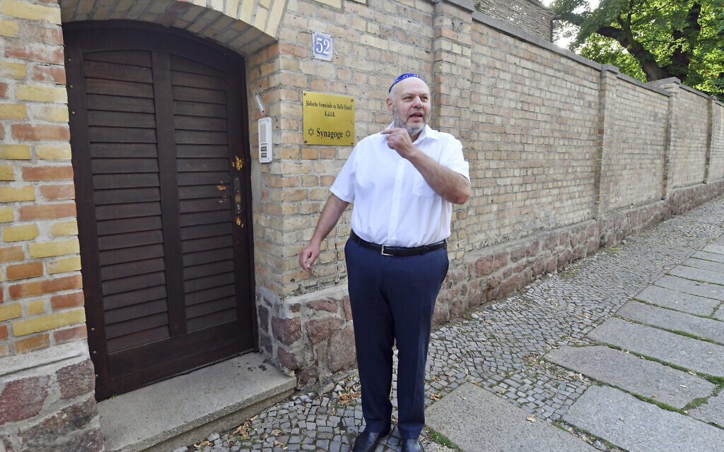 Max Privorozki, chairman of the Jewish community in Halle, stands in front the bullet hole-ridden door of a synagogue before the door was replaced, in Halle, Germany, July 28, 2020. (Hendrik Schmidtpa/dpa via AP)