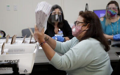 Illustrative: Miami-Dade County Department of Elections employee Elizabeth Prieto gathers vote-by-mail ballots for the August 18 primary election as the canvassing board meets to verify ballot signatures at the Miami-Dade County Elections Department, July 30, 2020, in Doral, Florida. (AP Photo/Lynne Sladky)