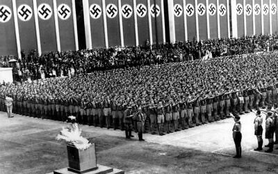 Nazi soldiers line up at attention during the opening ceremonies of the eleventh Summer Olympic Games at the Lustgarten in Berlin, Germany on August 1, 1936. The lighted Olympic torch is in the foreground. (AP Photo)