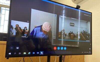 Malka Leifer (C) refuses to raise her head while appearing over Skype during an extradition hearing at the Jerusalem District Court on July 20, 2020. (Jacob Magid/Times of Israel)