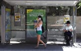 Illustrative: A woman talks on her mobile phone at a bus stop, in Tel Aviv, on August 24, 2012. (Yaakov Naumi/Flash90/File)