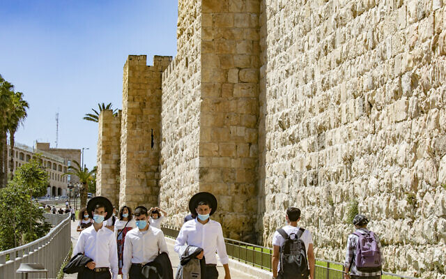 Jerusalemites wearing protective mask walk near the Jaffa Gate of the Old City of Jerusalem on June 23, 2020. (Olivier Fitoussi/Flash90) Jerusalemites wearing protective mask walk near the Jaffa Gate of the Old City of Jerusalem on June 23, 2020. (Olivier Fitoussi/Flash90)
