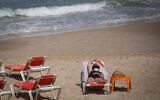 People wear protective face masks on the beach in Tel Aviv, on July 01, 2020. (Miriam Alster/FLASH90)