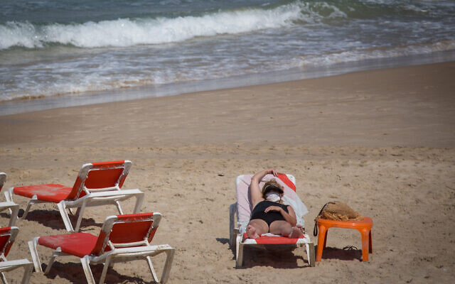 People wear protective face masks on the beach in Tel Aviv, on July 01, 2020. (Miriam Alster/FLASH90) People wear protective face masks on the beach in Tel Aviv, on July 01, 2020. (Miriam Alster/FLASH90)
