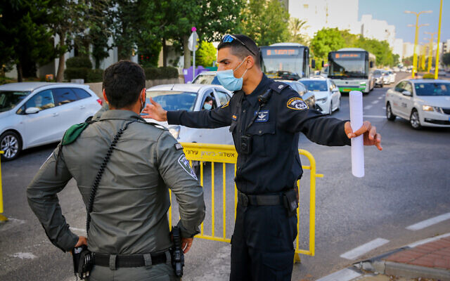 Police officers guard at the entrance to a neighborhood in the southern city of Ashdod, July 2, 2020, during a closure on some neighborhoods in the city following the spread of the coronavirus. (Flash90) Police officers guard at the entrance to a neighborhood in the southern city of Ashdod, July 2, 2020, during a closure on some neighborhoods in the city following the spread of the coronavirus. (Flash90)