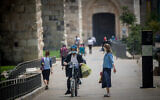 People walk wearing face masks walk near the Jaffa Gate outside Jerusalem's Old City on July 5, 2020. (Yonatan Sindel/Flash90)