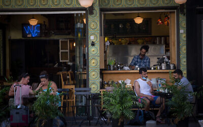 Illustrative: Israelis sit at a cafe in Tel Aviv on July 8, 2020. (Miriam Alster/Flash90)