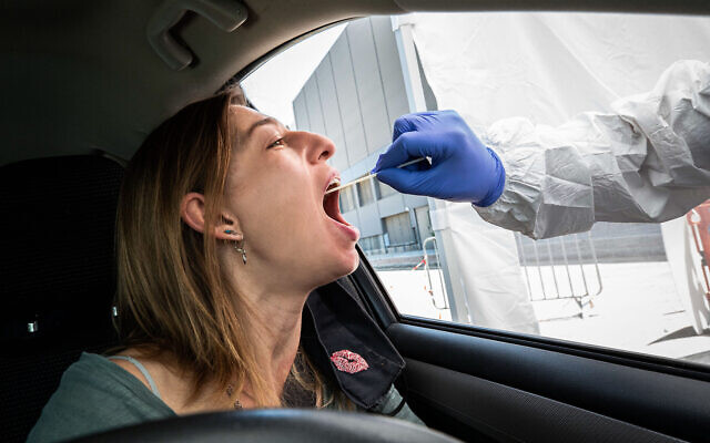 A Magen David Adom paramedic tests a woman at a drive-thru coronavirus testing site on July 11, 2020. (Chen Leopold/Flash90) A Magen David Adom paramedic tests a woman at a drive-thru coronavirus testing site on July 11, 2020. (Chen Leopold/Flash90)