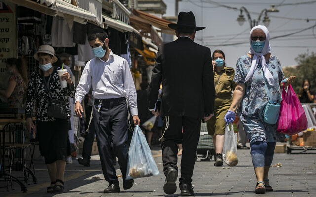 People wearing face masks shop for groceries at the Mahane Yehuda market in Jerusalem, on July 14, 2020. (Olivier Fitoussi/Flash90) People wearing face masks shop for groceries at the Mahane Yehuda market in Jerusalem, on July 14, 2020. (Olivier Fitoussi/Flash90)