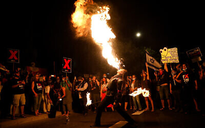 Demonstrators watch a fire show during a protest against Prime Minister Benjamin Netanyahu outside his official residence in Jerusalem on July 16, 2020. (Olivier Fitoussi/Flash90)