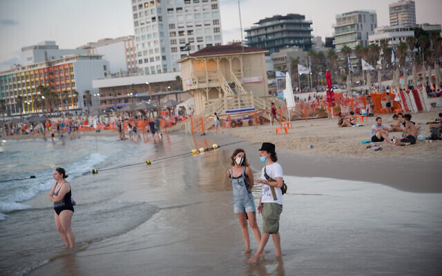 People wearing face masks due to the coronavirus outbreak enjoy the beach in Tel Aviv on July 18, 2020. (Miriam Alster/Flash90) People wearing face masks due to the coronavirus outbreak enjoy the beach in Tel Aviv on July 18, 2020. (Miriam Alster/Flash90)