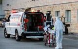 A Magen David Adom paramedic wearing protective clothing evacuates a patient with COVID-19, outside the coronavirus unit at Ziv Medical Center in Safed, July 19, 2020. (David Cohen/Flash90)