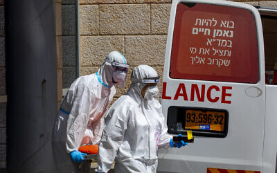 Magen David Adom ambulance crew wearing protective clothing after delivering a man suspected of infection with the coronavirus to  Hadassah Ein Kerem Medical Center, in Jerusalem, on July 20, 2020.(Olivier Fitoussi/Flash90)