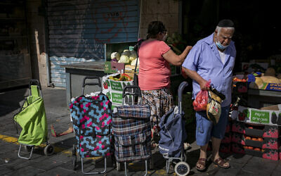 People wearing face masks due to the coronavirus outbreak shop for groceries at the Mahane Yehuda market in Jerusalem on July 21, 2020. (Olivier Fitoussi/Flash90)