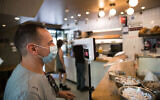 A man checks his body temperature as he enters a coffee shop in Jerusalem on July 21, 2020 (Yonatan Sindel/Flash90)
