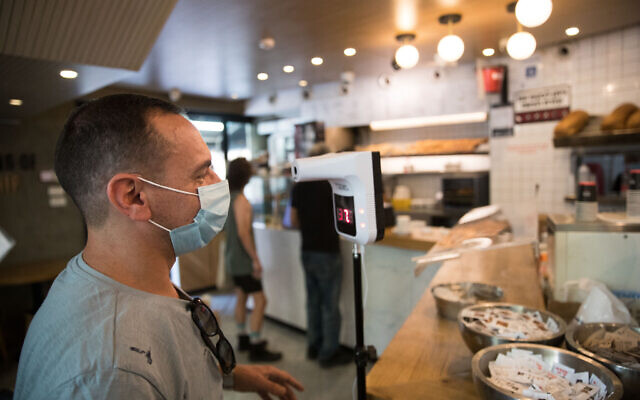 A man checks his body temperature as he enters a coffee shop in Jerusalem on July 21, 2020 (Yonatan Sindel/Flash90) A man checks his body temperature as he enters a coffee shop in Jerusalem on July 21, 2020 (Yonatan Sindel/Flash90)