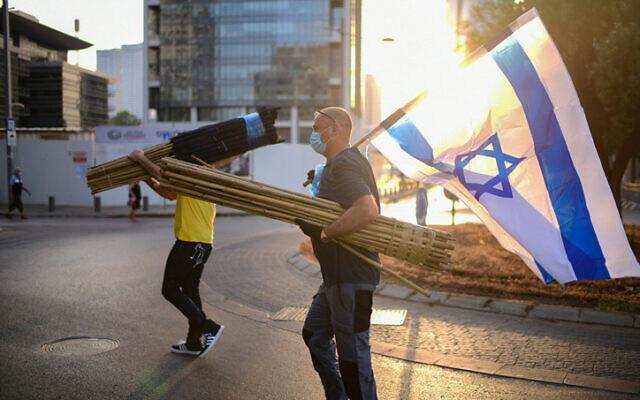 A protester carrying an Israeli flag near the home of Public Security Minister Amir Ohana on July 28, 2020 in Tel Aviv. (Tomer Neuberg/Flash90)