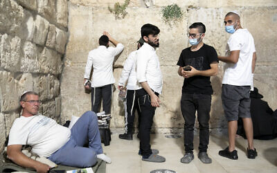 Jewish men pray at the Western Wall on the eve of Tisha B'Av in the Old City of Jerusalem, on July 29, 2020. (Olivier Fitoussi/Flash90)