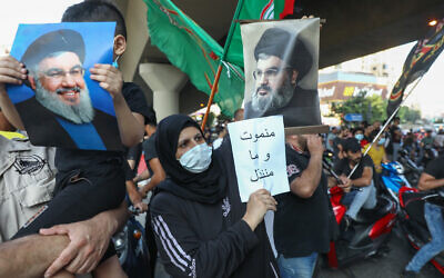 Hezbollah supporters lift pictures of its terror chief Hassan Nasrallah and anti-US placards as they protest a statement made by the US ambassador criticizing the group at a rally in the southern suburb of the capital Beirut, June 28, 2020. (Anwar Amro/AFP)
