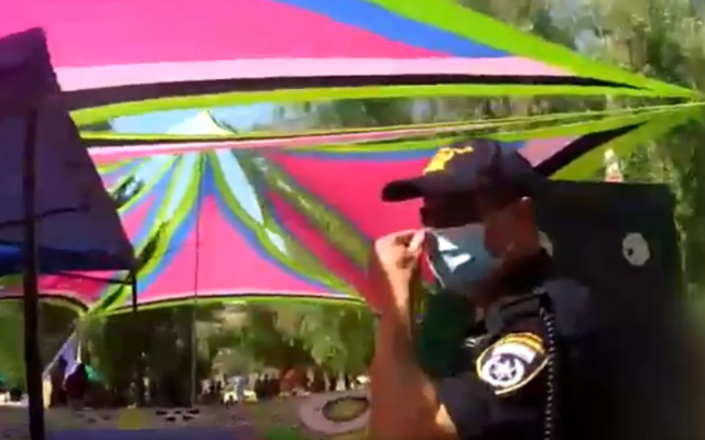 A police officer at the site of an outdoor rave held in violation of social distancing rules at a forest near Modiin, July 18, 2020. (Screenshot: Twitter/Israel Police) A police officer at the site of an outdoor rave held in violation of social distancing rules at a forest near Modiin, July 18, 2020. (Screenshot: Twitter/Israel Police)