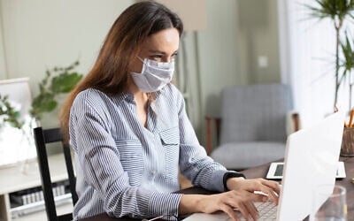 Illustrative: A woman wearing a mask works in the office on a laptop (eternalcreative; iStock by Getty Images) Illustrative: A woman wearing a mask works in the office on a laptop (eternalcreative; iStock by Getty Images)