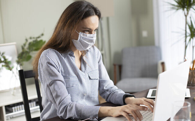 Illustrative: A woman wearing a mask works in the office on a laptop (eternalcreative; iStock by Getty Images) Illustrative: A woman wearing a mask works in the office on a laptop (eternalcreative; iStock by Getty Images)