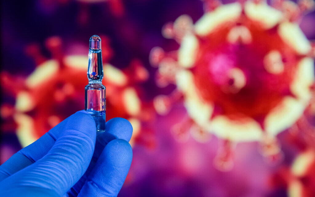 Coronavirus vaccine. A hand in medical gloves holds a vaccine and a syringe against the background of the image of the novel coronavirus. (iStock) Coronavirus vaccine. A hand in medical gloves holds a vaccine and a syringe against the background of the image of the novel coronavirus. (iStock)