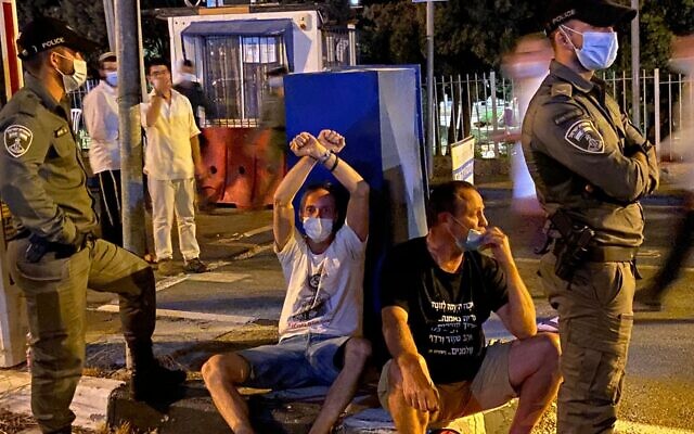 Protesters sitting by police as water cannons dispersed demonstrators at anti-Netanyahu rally on Agron Street (Anat Peled/Times of Israel) Protesters sitting by police as water cannons dispersed demonstrators at anti-Netanyahu rally on Agron Street (Anat Peled/Times of Israel)