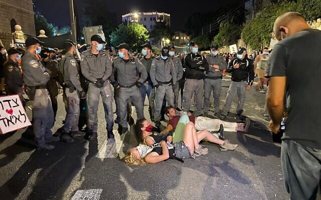 Protesters lie down in front of riot police on Ben Maimon Street outside the Prime Minister's Residence in Jerusalem on Sunday, July 26, 2020. (Anat Peled/Times of Israel)