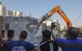 Relatives of the Shalalda family watch as an excavator hired by them demolishes their family home in Al-Tur in east Jerusalem on July 2, 2020 (AHMAD GHARABLI / AFP)