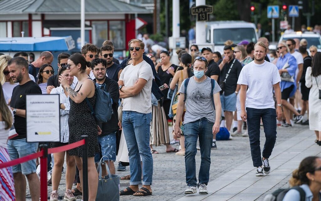 A man wearing a protective mask walks next to travelers as they queue up to board a boat at Stranvagen in Stockholm on July 27, 2020, during the novel coronavirus / COVID-19 pandemic. (Jonathan NACKSTRAND / AFP) A man wearing a protective mask walks next to travelers as they queue up to board a boat at Stranvagen in Stockholm on July 27, 2020, during the novel coronavirus / COVID-19 pandemic. (Jonathan NACKSTRAND / AFP)