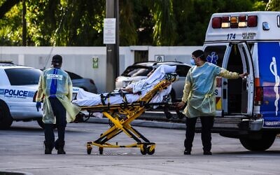 Medics transfer a patient on a stretcher from an ambulance outside of the emergency room at Coral Gables Hospital, where coronavirus patients are treated in Coral Gables, Florida, on July 30, 2020. (Chandan Khanna/AFP)