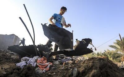 A youth moves debris on a rooftop following an Israeli air strike east of al-Bureij in the central Gaza Strip on August 15, 2020. (MAHMUD HAMS / AFP)