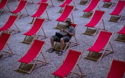 In this photo taken on July 18, 2020, a man waits for the start of a video projection in the "Cour d'Honneur du Palais des Papes" in Avignon, southern France. (CLEMENT MAHOUDEAU/AFP)