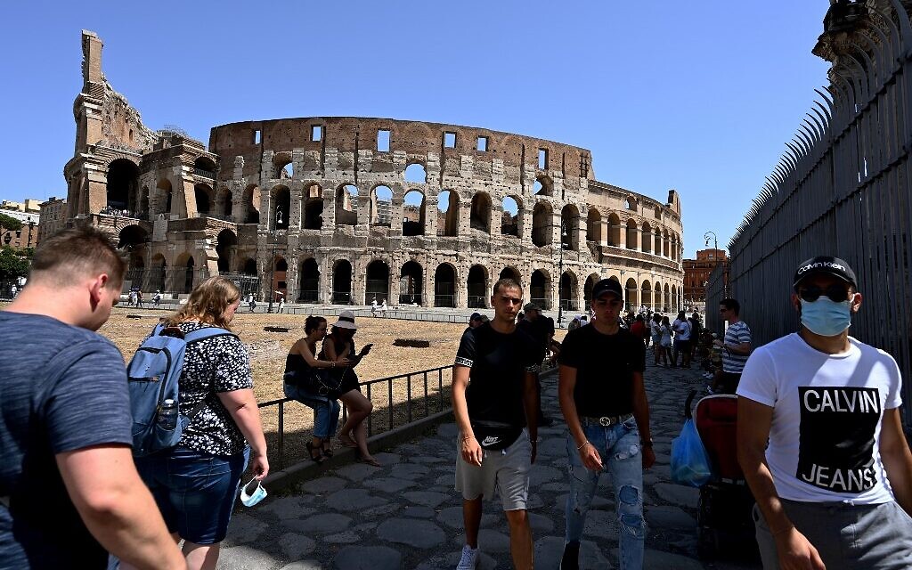 Tourists, some wearing a face mask, walk outside the Colosseum monument on August 22, 2020 in Rome during the COVID-19 infection, caused by the novel coronavirus.  (Vincenzo PINTO / AFP)