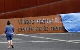 A visitor looks at graffiti tags seen on the lettering at the entrance to the Centre of Oradour sur Glane Memory, the village where German Waffen-SS troops massacred 642 of its inhabitants in June 1944, in Oradour-sur-Glane, west-central France, on August 22, 2020. (PASCAL LACHENAUD / AFP)