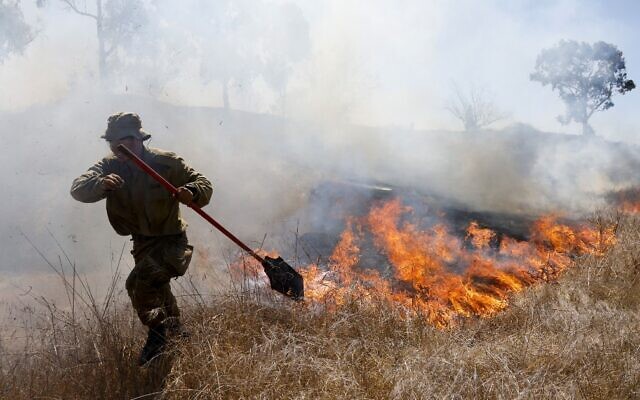 An Israeli soldier battles a blaze close to the southern kibbutz of Nir Am that was apparently caused by a balloon-borne incendiary device launched from the Gaza Strip, August 23, 2020. (Menahem Kahana/AFP) An Israeli soldier battles a blaze close to the southern kibbutz of Nir Am that was apparently caused by a balloon-borne incendiary device launched from the Gaza Strip, August 23, 2020. (Menahem Kahana/AFP)