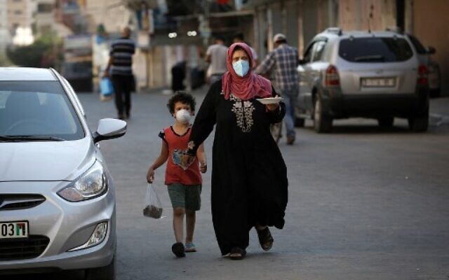 A Palestinian woman carries a plate of food as she walks alongside her child, both clad in masks, in Gaza City on August 28, 2020, during a lockdown in the Palestinian enclave due to increasing cases of COVID-19 infections. (Mohammed Abed/AFP) A Palestinian woman carries a plate of food as she walks alongside her child, both clad in masks, in Gaza City on August 28, 2020, during a lockdown in the Palestinian enclave due to increasing cases of COVID-19 infections. (Mohammed Abed/AFP)